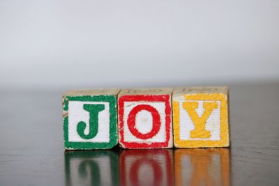 Close-up of colorful joy text on table against white background