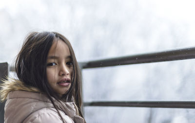 Portrait of young woman with snow against sky