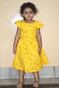 Portrait of girl standing against yellow wall