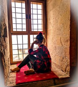 Woman sitting on window sill at home