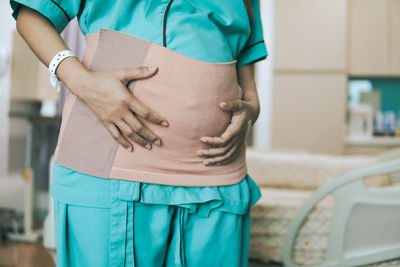 Midsection of woman standing against wall