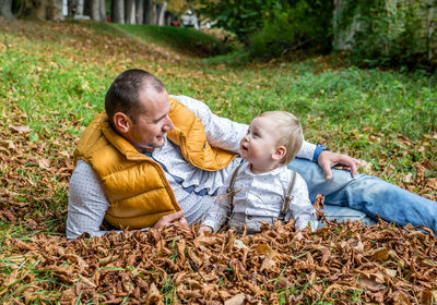 Father and son in leafs outdoor smiling