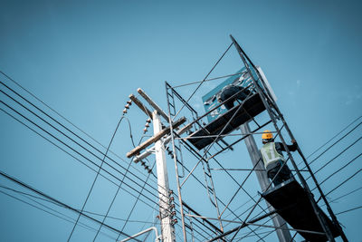 Low angle view of electricity pylon against blue sky