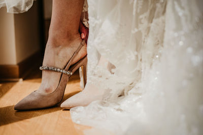 Low section of woman wearing high heels on hardwood floor