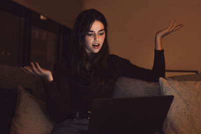 Portrait of young woman using laptop at home