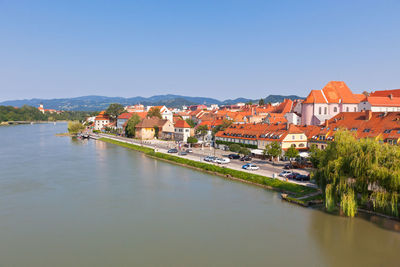 Buildings by river against clear sky