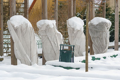 Plants and trees in a park or garden covered by the snow and blanket, swath of burlap