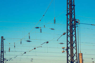 Low angle view of transformers on cable against blue sky