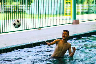 Full length of shirtless man playing in swimming pool