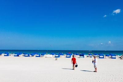 People on beach against blue sky