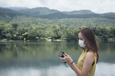 Side view of woman photographing lake