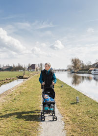 Grandfather pushing granddaughter stroller at lakeshore