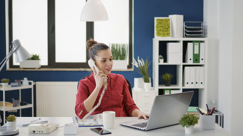 Smiling businesswoman talking on phone at office