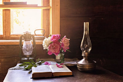 Still life of vintage items and a bouquet of peonies on a table by the window in village house