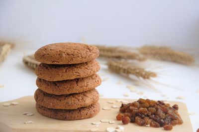 Biscuits on a wooden board next to raisins and raw oatmeal