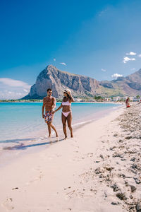 Rear view of people on beach against sky