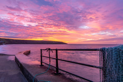 Scenic view of sea against dramatic sky during sunset