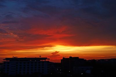 Silhouette buildings against dramatic sky during sunset