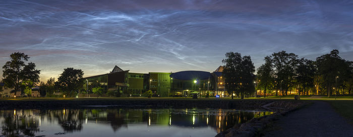 Reflection of trees and buildings in lake against sky