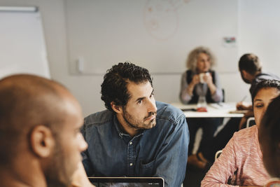 Friends discussing while man sitting with teacher at language class