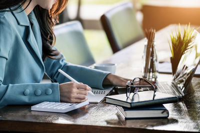 Midsection of woman using laptop on table