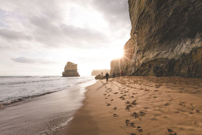 Scenic view of beach against cloudy sky during sunny day