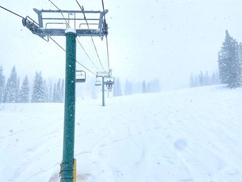 Ski lift on snow covered field against sky