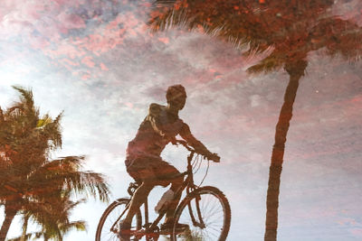 Low angle view of man riding bicycle against sky