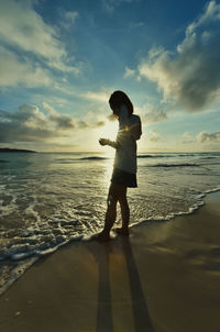 Full length of man standing on beach during sunset