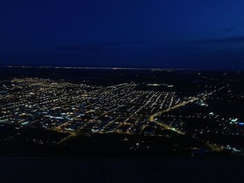 Aerial view of illuminated cityscape against blue sky