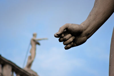 Low angle view of hand statue against sky