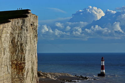 Beachy head lighthouse in sea at seven sisters against sky