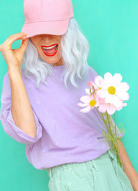 Woman wearing cap with pink flower against blue background