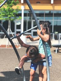 Siblings climbing on play equipment at playground