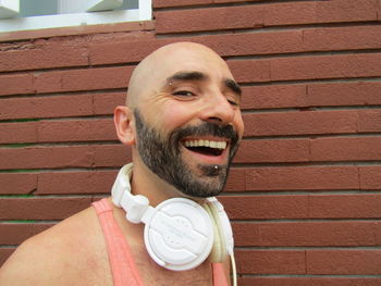 Portrait of man smiling against brick wall
