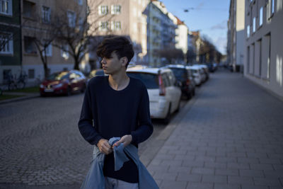 Young man walking on sidewalk in city