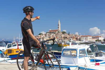 Man riding bicycle at harbor against sky