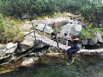 Full length of woman standing by river in forest