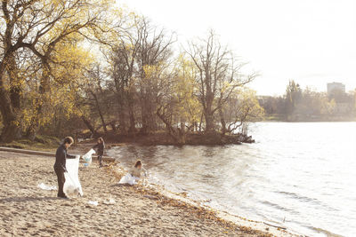 Female volunteer with friends collecting plastic garbage by lake