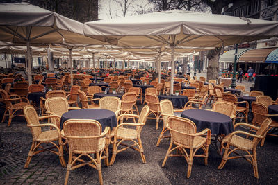 Empty chairs and tables at sidewalk cafe