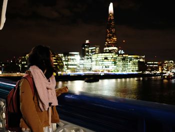 Rear view of woman standing in illuminated city at night