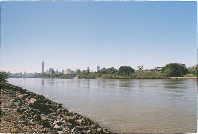 Scenic view of river by buildings against clear sky