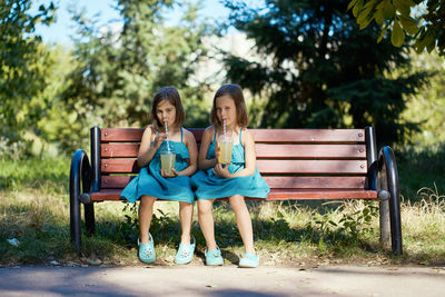 Two little girls drinking lemonade in park