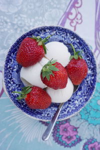 High angle view of strawberries and ice cream in plate on table