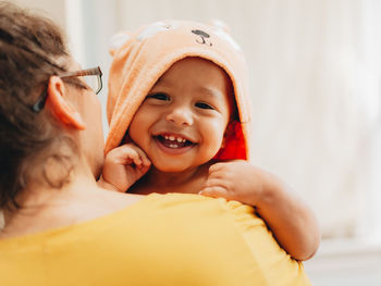 Portrait of cute smiling boy with mother sitting at home