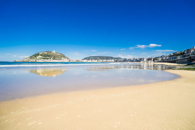 Scenic view of beach against blue sky