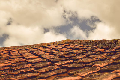 View of roof tiles against cloudy sky