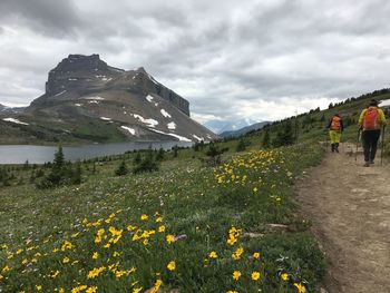 People on mountain against cloudy sky