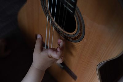 Cropped hand of baby boy on guitar