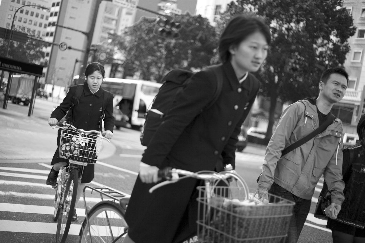 bicycle, city, real people, transportation, adult, men, lifestyles, focus on foreground, casual clothing, street, young adult, architecture, people, women, incidental people, day, mode of transportation, bag, basket, outdoors, riding